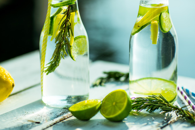 Garrafas com água DETOX de limão, além de outros ingredientes na mesa.