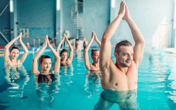 Pessoas de diversas idades praticando exercícios físicos - hidroginástica - durante o verão